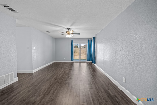 empty room with ceiling fan, dark wood-type flooring, and a textured ceiling