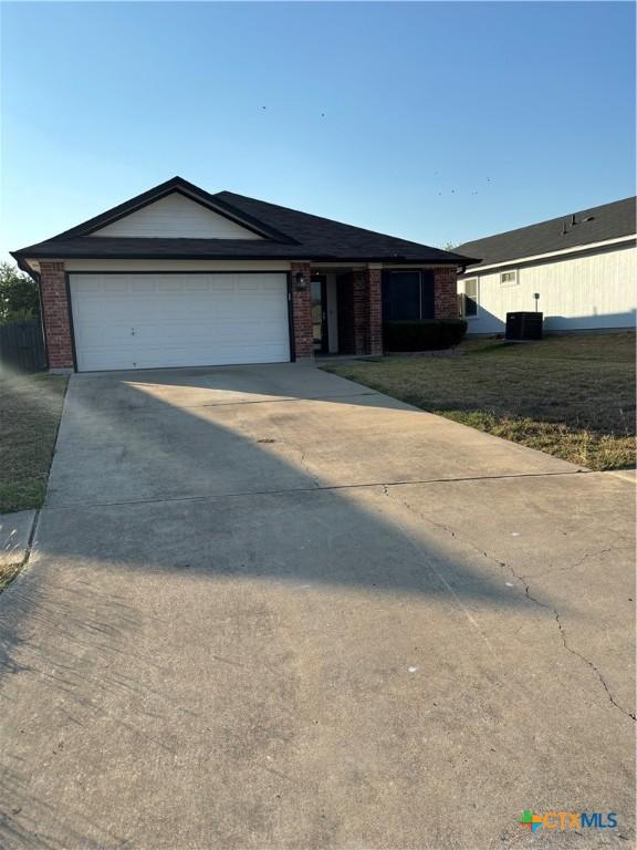 single story home featuring central AC, a front lawn, and a garage