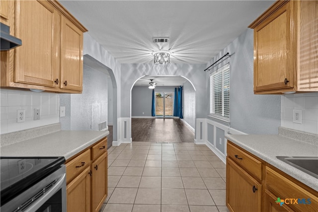 kitchen with ceiling fan, range hood, stainless steel range with electric cooktop, decorative backsplash, and light tile patterned floors