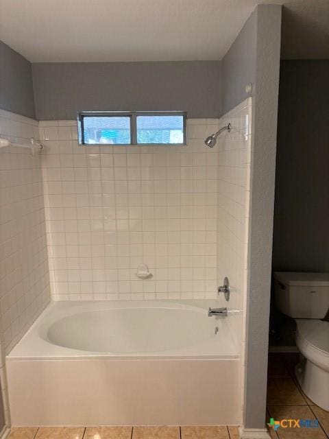 bathroom featuring tile patterned floors, tiled shower / bath, and toilet