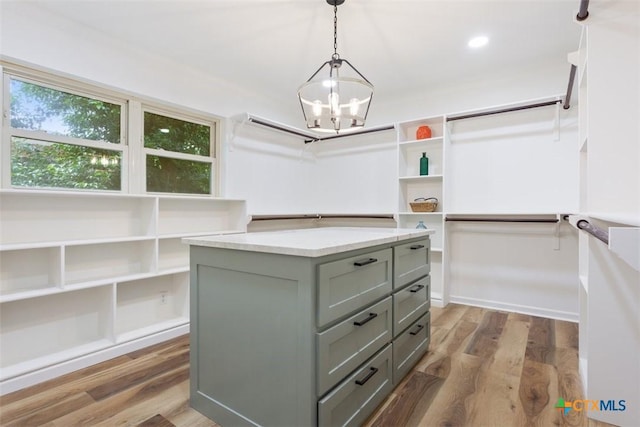 walk in closet with a chandelier and wood finished floors