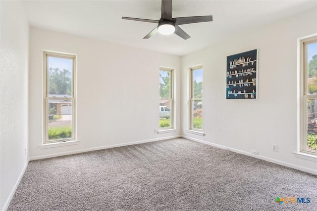 carpeted empty room featuring ceiling fan, baseboards, and a healthy amount of sunlight