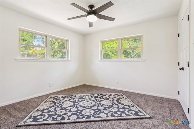 carpeted empty room with a wealth of natural light, a ceiling fan, and baseboards