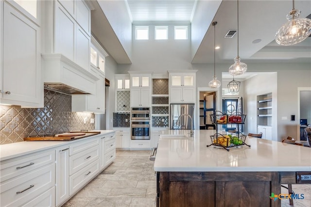 kitchen with hanging light fixtures, sink, a kitchen island with sink, and appliances with stainless steel finishes