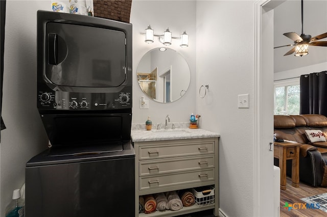 bathroom with ceiling fan, vanity, stacked washing maching and dryer, and hardwood / wood-style floors