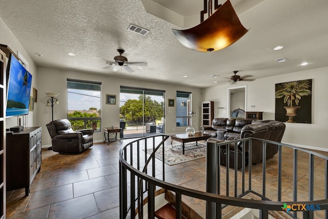 interior space with a textured ceiling, tile patterned floors, and ceiling fan