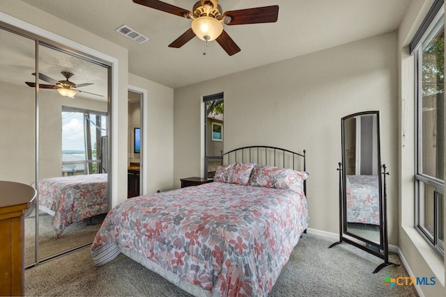 carpeted bedroom with multiple windows, ceiling fan, and a closet