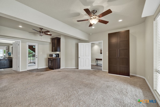 unfurnished living room featuring carpet, a textured ceiling, and ceiling fan