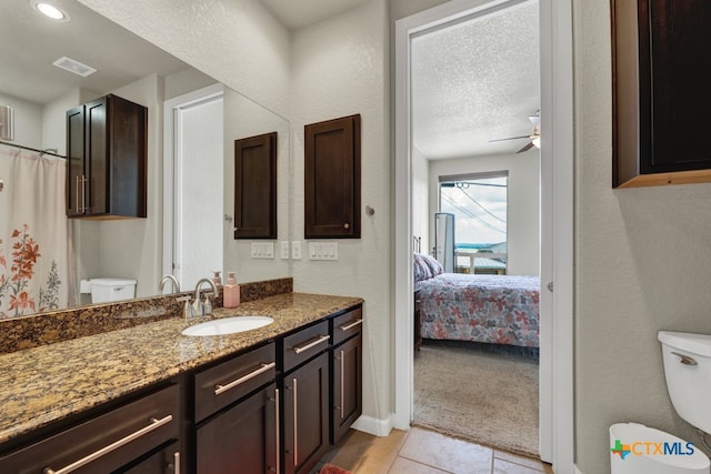 bathroom with toilet, tile patterned floors, a textured ceiling, vanity, and ceiling fan