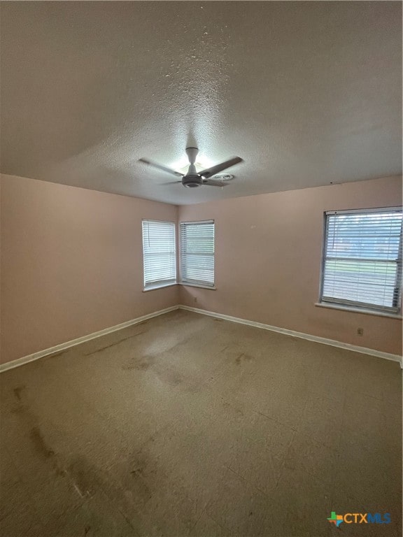 spare room with a wealth of natural light, ceiling fan, and a textured ceiling