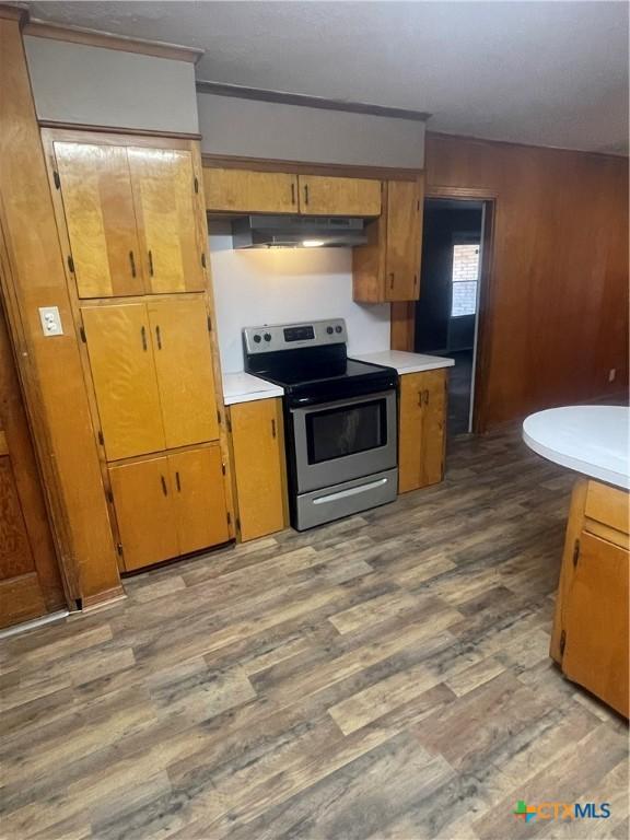 kitchen featuring light countertops, stainless steel electric stove, wood finished floors, and under cabinet range hood