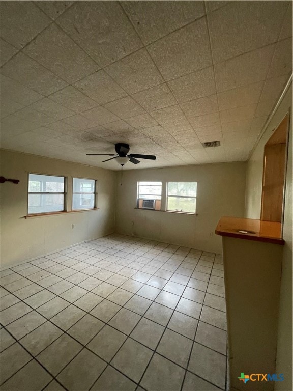 tiled empty room featuring cooling unit, a healthy amount of sunlight, and ceiling fan