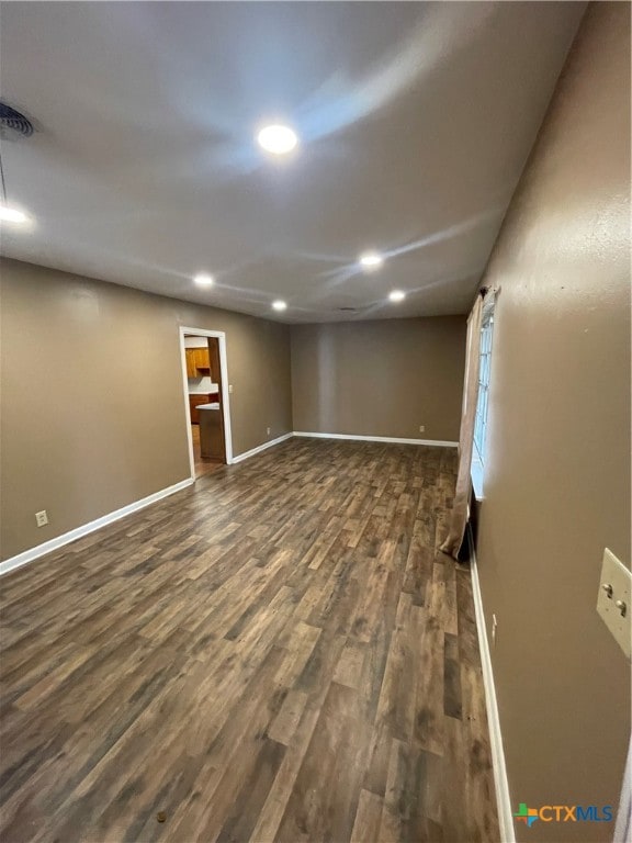 below grade area featuring dark wood-type flooring, recessed lighting, visible vents, and baseboards