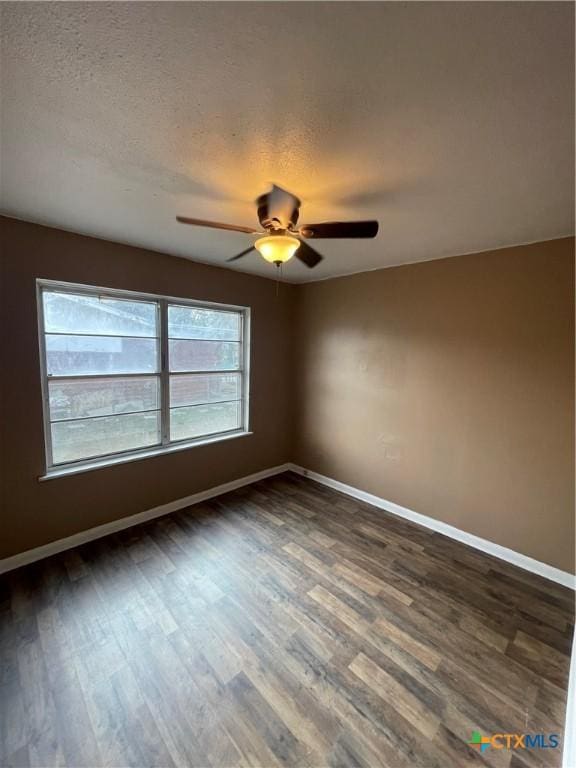 empty room featuring a textured ceiling, baseboards, dark wood-style flooring, and ceiling fan