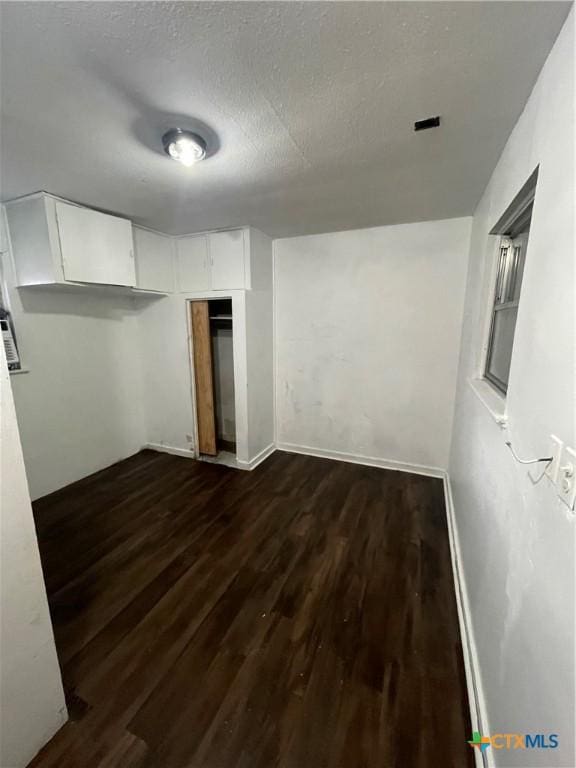 below grade area featuring dark wood finished floors, a textured ceiling, and baseboards