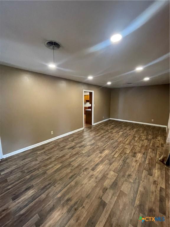 finished basement featuring recessed lighting, visible vents, baseboards, and dark wood finished floors