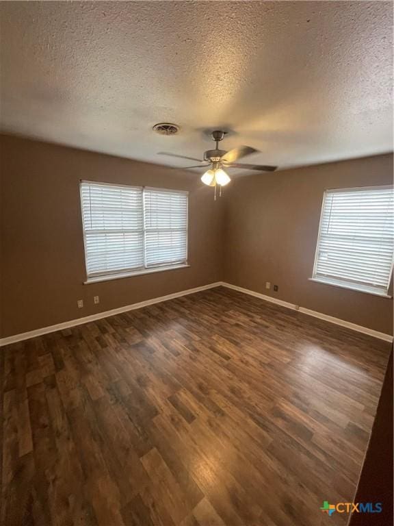 unfurnished room with ceiling fan, baseboards, plenty of natural light, and dark wood-style floors