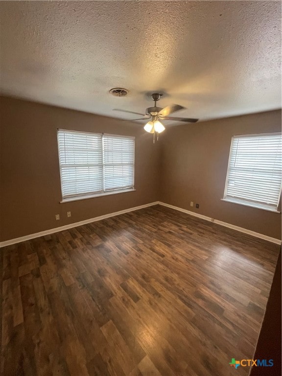 empty room with dark wood-type flooring, ceiling fan, a textured ceiling, and a healthy amount of sunlight