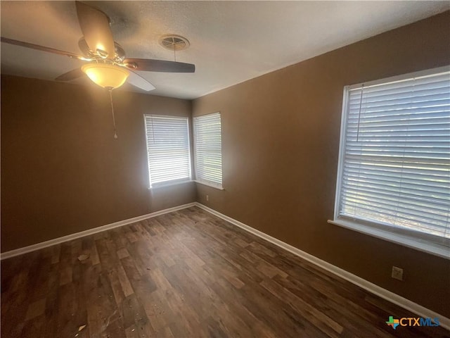 unfurnished room with visible vents, baseboards, dark wood-style flooring, and a ceiling fan