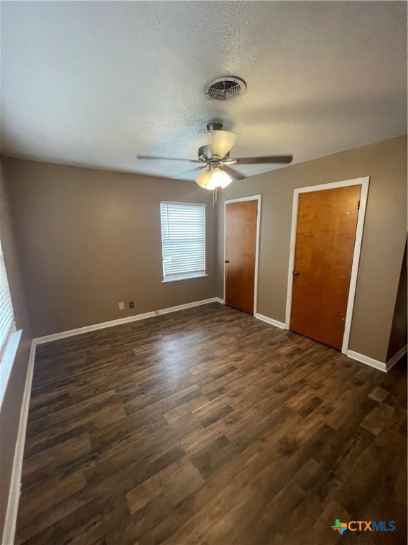 unfurnished bedroom with a textured ceiling, dark hardwood / wood-style flooring, and ceiling fan