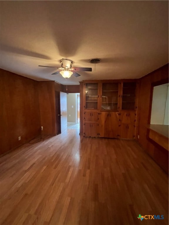 unfurnished living room featuring ceiling fan, wood-type flooring, and built in features