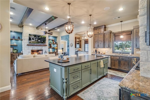 kitchen with dark wood-style flooring, visible vents, green cabinets, a sink, and a stone fireplace