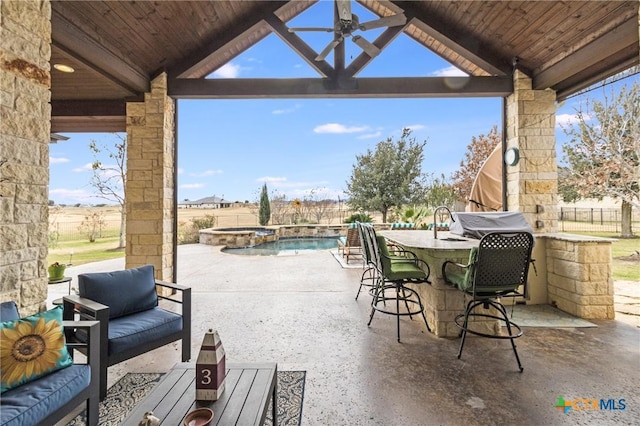 view of patio with area for grilling, an outdoor hangout area, outdoor dry bar, fence, and a pool with connected hot tub