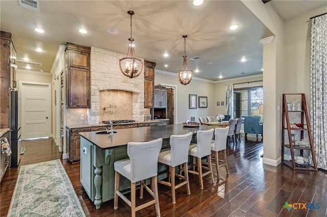 kitchen with visible vents, decorative backsplash, dark wood-style flooring, freestanding refrigerator, and a kitchen island with sink