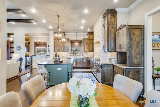 kitchen with pendant lighting, backsplash, hardwood / wood-style floors, ornamental molding, and a kitchen island