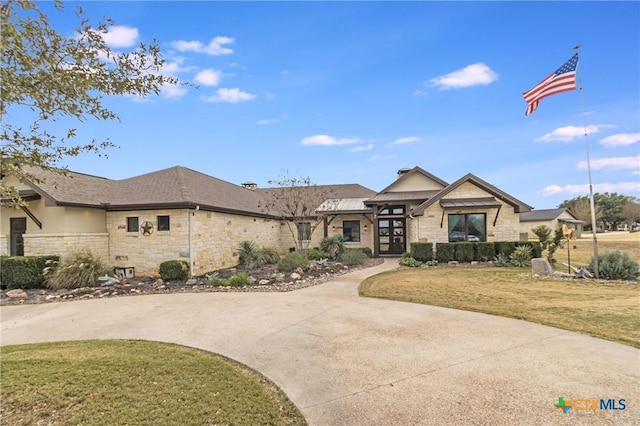 view of front of property with stone siding, a front lawn, and concrete driveway