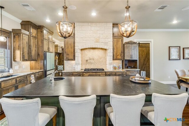 kitchen featuring stainless steel gas cooktop, ornamental molding, sink, and backsplash