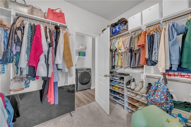 spacious closet featuring washer / clothes dryer and light colored carpet