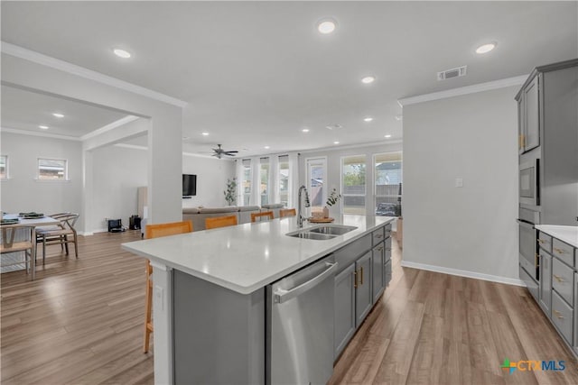 kitchen featuring an island with sink, appliances with stainless steel finishes, gray cabinets, and sink