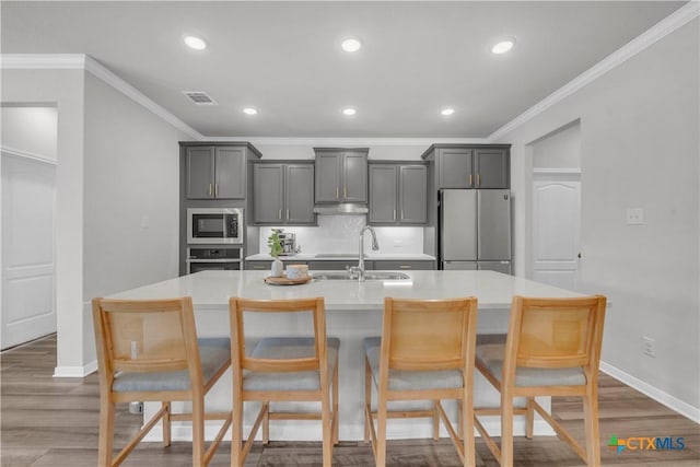 kitchen featuring gray cabinets, a center island with sink, stainless steel appliances, dark wood-type flooring, and sink