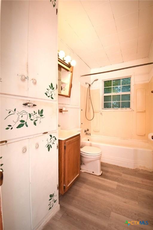 bathroom with toilet, vanity,  shower combination, and wood finished floors