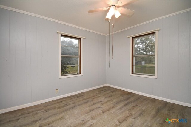 unfurnished room featuring a healthy amount of sunlight, wood finished floors, and crown molding