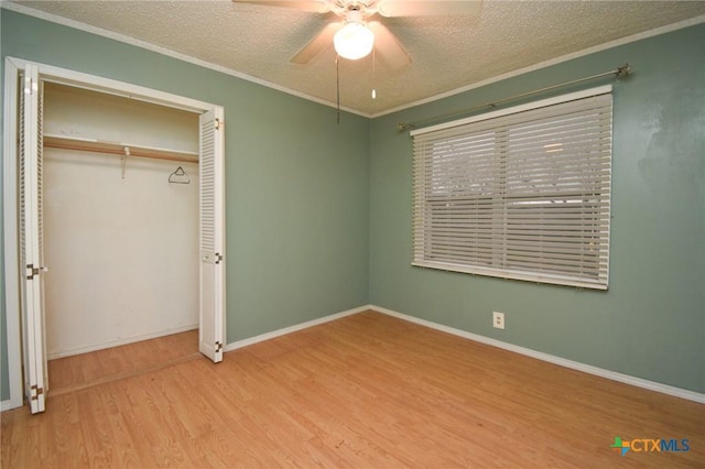 unfurnished bedroom featuring crown molding, wood finished floors, a closet, and a textured ceiling