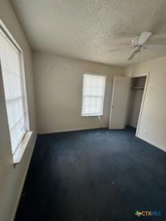 unfurnished bedroom featuring ceiling fan, a textured ceiling, and a closet