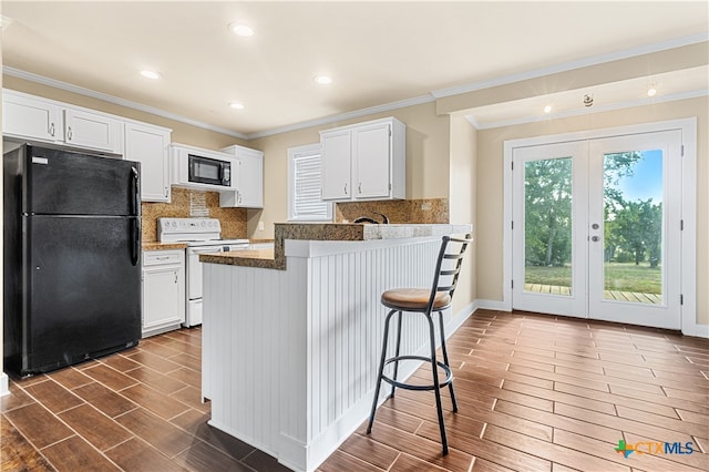 kitchen with white cabinets, ornamental molding, black appliances, and dark wood-type flooring