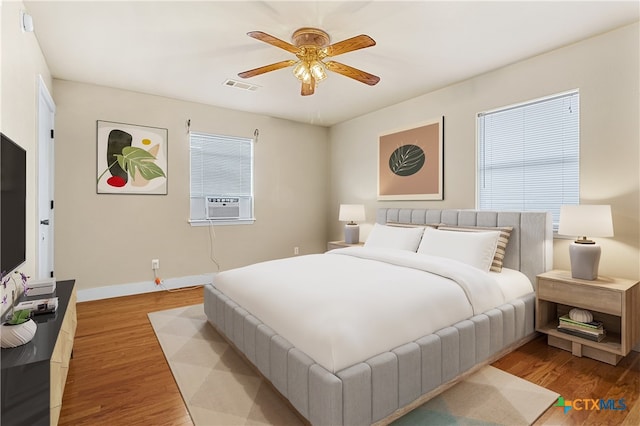 bedroom featuring light hardwood / wood-style flooring, cooling unit, and ceiling fan