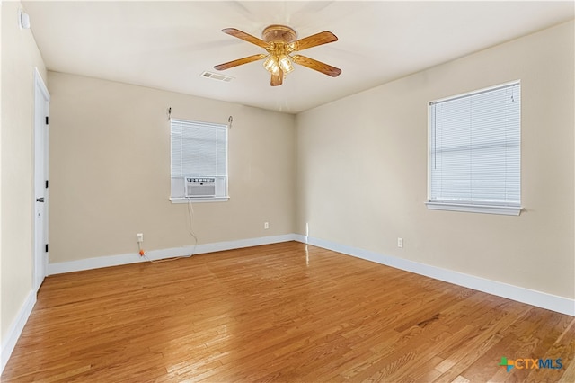 empty room with hardwood / wood-style floors, a wealth of natural light, ceiling fan, and cooling unit