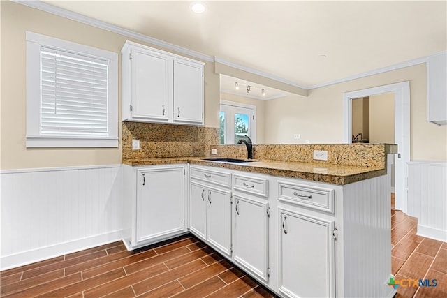 kitchen with ornamental molding, stone counters, sink, white cabinets, and dark wood-type flooring