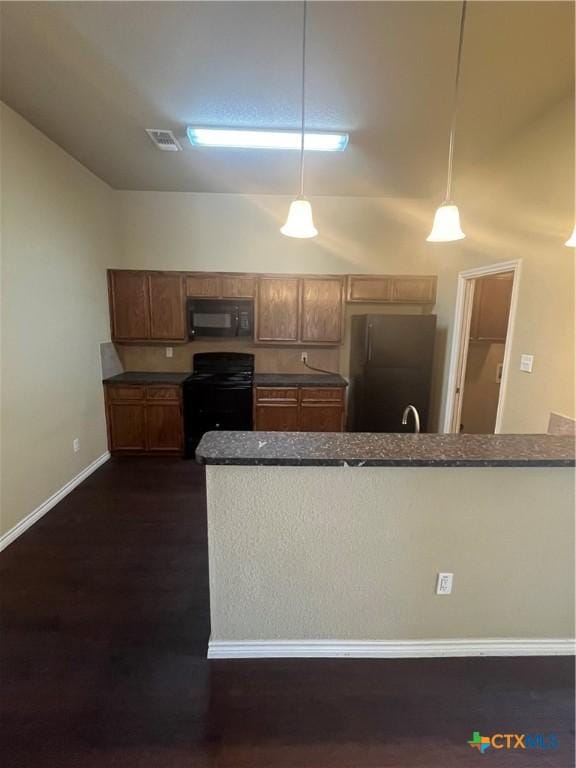 kitchen featuring visible vents, dark wood finished floors, freestanding refrigerator, black microwave, and range