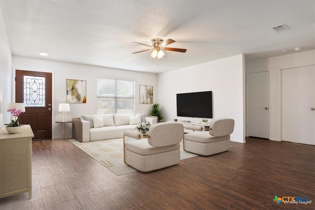 living room featuring dark hardwood / wood-style flooring, a textured ceiling, and ceiling fan