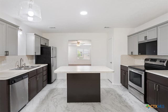 kitchen featuring stainless steel appliances, gray cabinets, sink, and backsplash