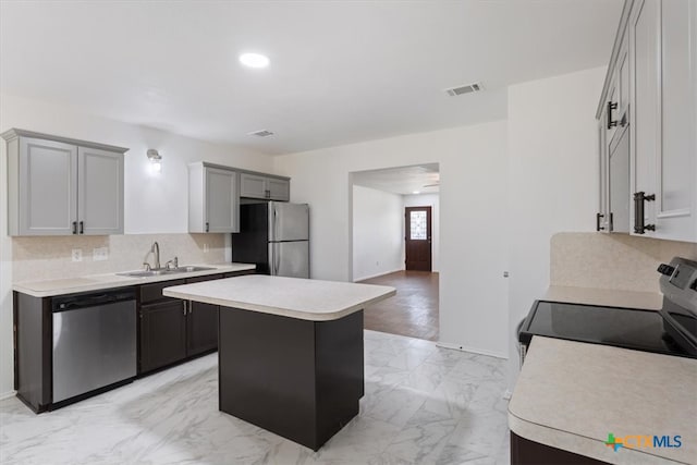 kitchen featuring a center island, sink, tasteful backsplash, gray cabinets, and appliances with stainless steel finishes