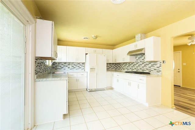 3003 Zephyr Rd, Killeen, TX 76543 - kitchen with white fridge with ice dispenser, under cabinet range hood, light countertops, backsplash, and light tile patterned floors