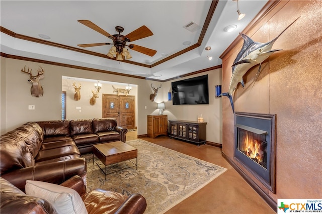 living room featuring ornamental molding, ceiling fan, and a raised ceiling