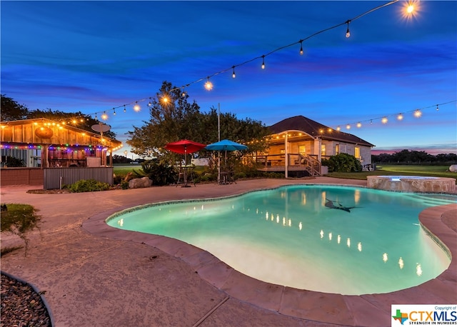 pool at dusk with a patio area