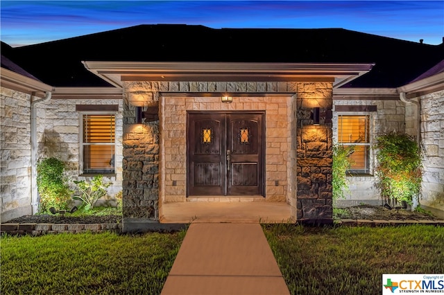 exterior entry at dusk featuring a lawn